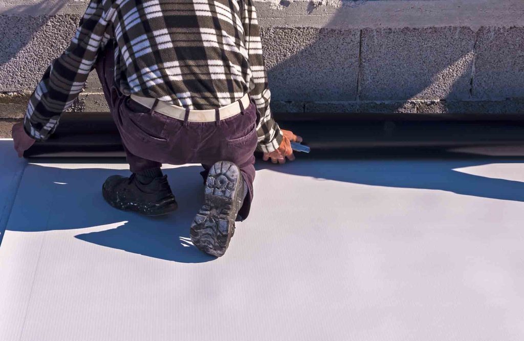 Roofer applying a coating to a flat roof