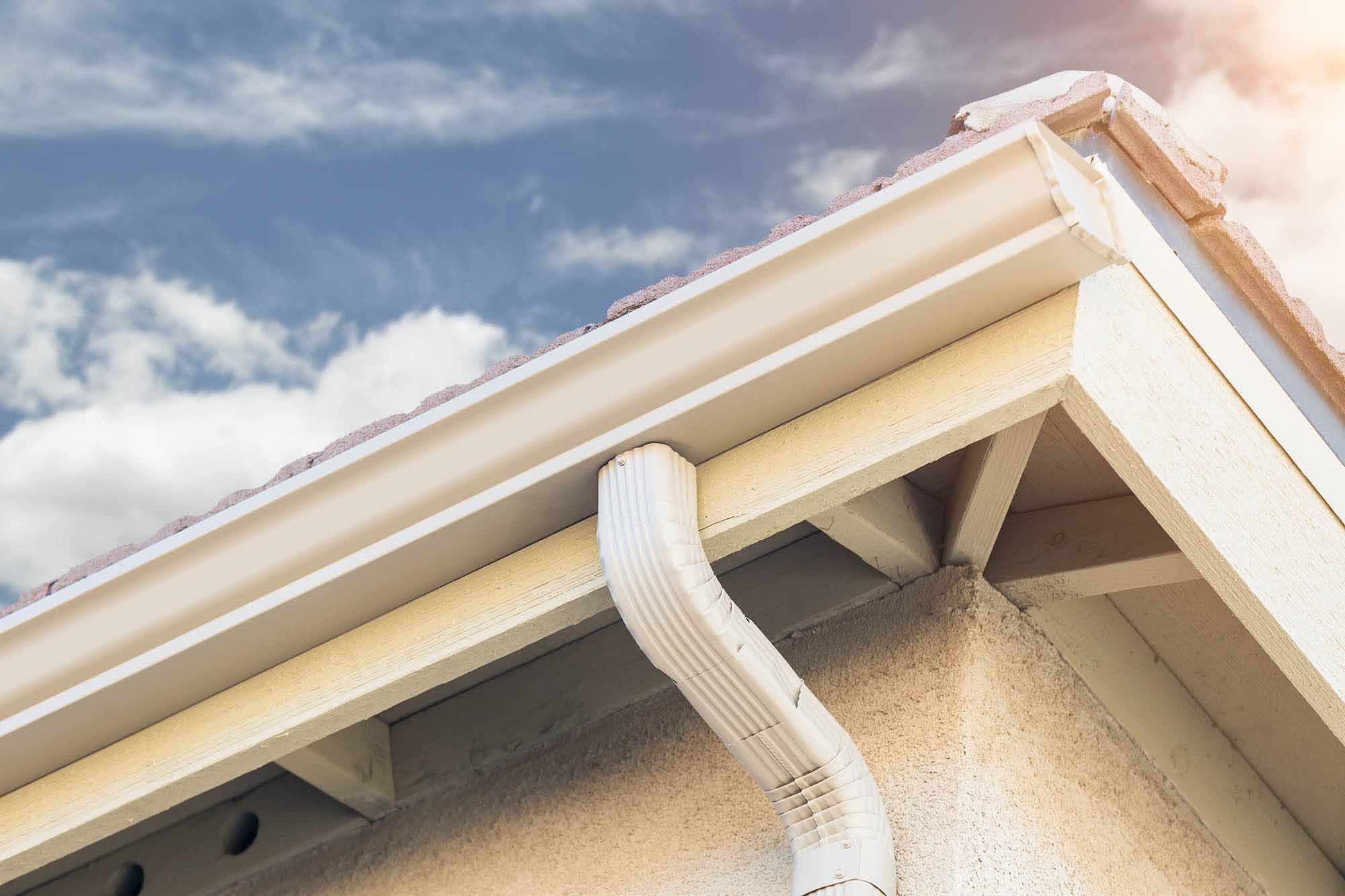 White seamless gutter and downspout on a home roofline
