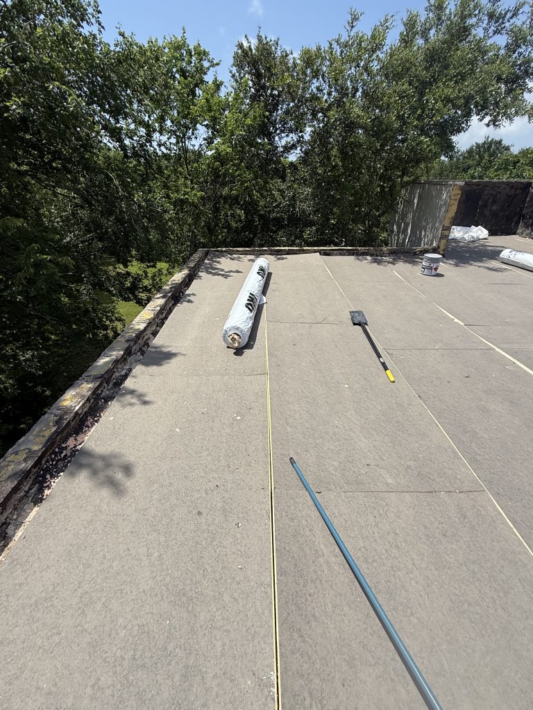 Flat roof base layer being installed with materials on the deck