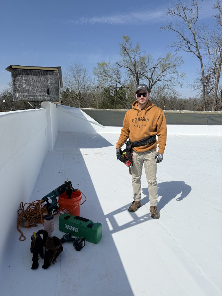 Talton Roofing crew member on a white flat commercial roof with tools