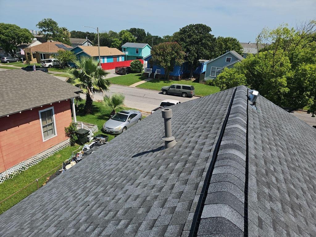 New dark shingle roof with ridge vent in a coastal neighborhood