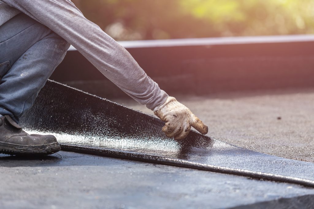 Roofer sealing a seam on a flat roof membrane