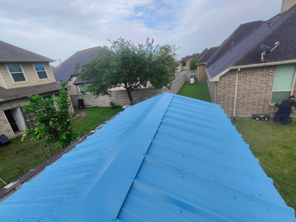 Blue synthetic underlayment installed on a roof ridge before shingles