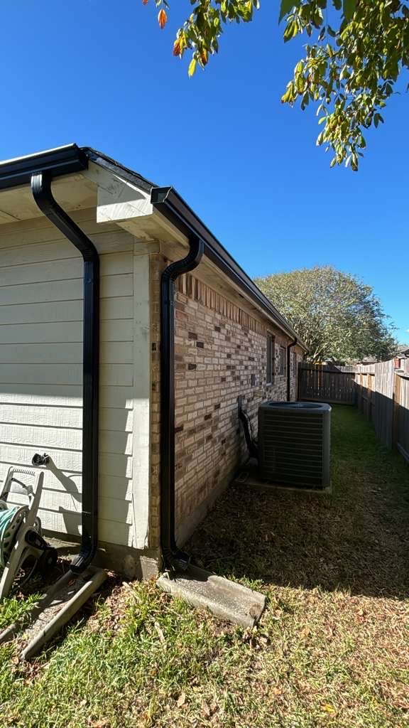 Black gutters and downspouts installed on a brick home