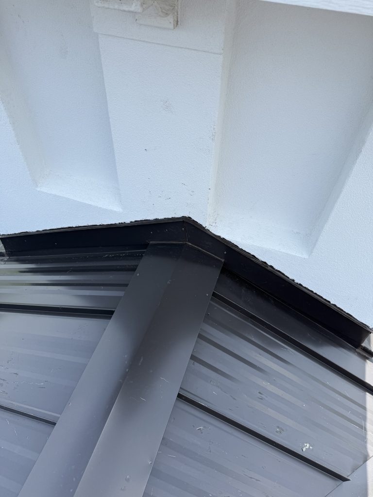 Dark metal panel roof and trim detail against white siding