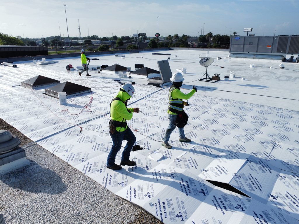 Roofing crew rolling out new membrane on a commercial flat roof