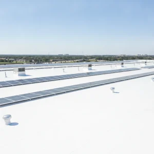 A modern, clean TPO commercial roof on a large building in Greater Houston, with a clear blue sky, showing reflective white surface. No text in image, no text overlays, no fake looking AI renders, no generic stock photos, no poorly maintained roofs.